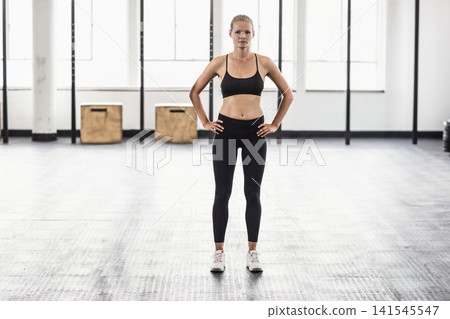 Woman standing centered in gym on rubber floor, wearing black bra and leggings near plyo boxes 141545547
