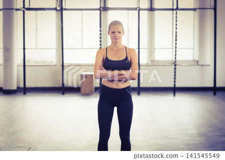 Woman in her 20s standing centered in fitness studio, wearing black sportswear, pull-up rig behind Woman in her 20s standing centered in fitness studio, wearing black sportswear, pull-up rig behind 141545549