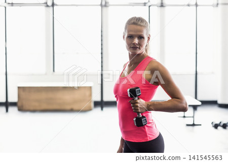 Female in bright pink top and black leggings lifting hex dumbbell in fitness studio, copy space Female in bright pink top and black leggings lifting hex dumbbell in fitness studio, copy space 141545563