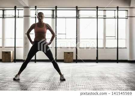 Female standing in gym wearing pink sports bra and dark leggings near plyo boxes and rig Female standing in gym wearing pink sports bra and dark leggings near plyo boxes and rig 141545569