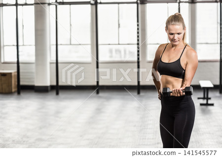 Woman performing hex dumbbell curl, wearing black sports bra and leggings in gym, copy space Woman performing hex dumbbell curl, wearing black sports bra and leggings in gym, copy space 141545577