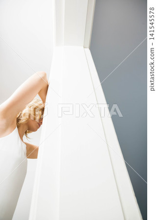 Female posing, lifting hands behind head at left near pillar in sleeveless top, copy space Female posing, lifting hands behind head at left near pillar in sleeveless top, copy space 141545578