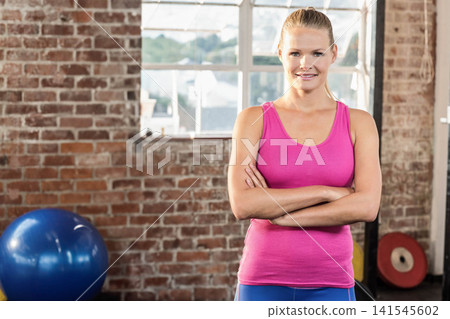 Female wearing pink tank and blue leggings standing by brick wall with stability ball, copy space Female wearing pink tank and blue leggings standing by brick wall with stability ball, copy space 141545602