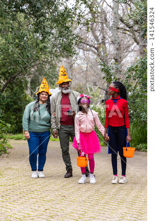 African American family walking on park path, senior, teenage and child carrying orange buckets African American family walking on park path, senior, teenage and child carrying orange buckets 141546324