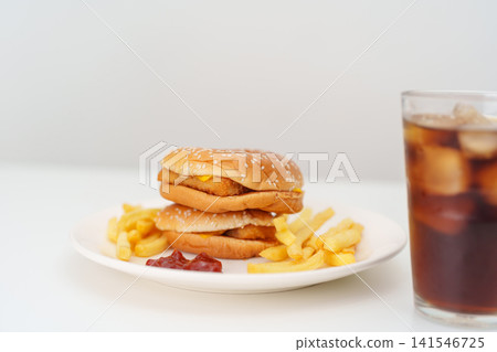 juicy beef burger with melted cheddar cheese, potato chips and carbonated Soft drinks on table. Unhealthy, High calorie, Fast food craving, Obesity, diet, weight loss, junk food and lifestyle juicy beef burger with melted cheddar cheese, potato chips and carbonated Soft drinks on table. Unhealthy, High calorie, Fast food craving, Obesity, diet, weight loss, junk food and lifestyle 141546725