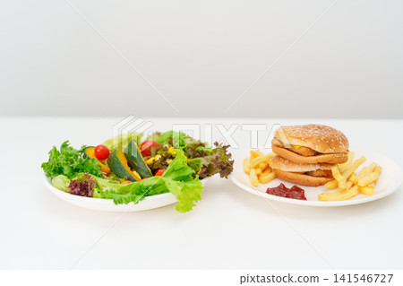 Healthy and Unhealthy Food Choice. Comparison of Calories and Nutrition of vegetables Salad plate and Hamburger. Concept for diet planning, weight loss management, junk food and habit lifestyle 141546727