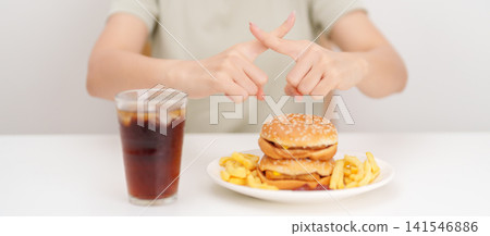Unhappy woman showing Rejecting and refusing with Juicy beef burger, potato chips and carbonated Soft drinks. Unhealthy, High calorie, Fast food craving, Obesity, diet, weight loss and junk food Unhappy woman showing Rejecting and refusing with Juicy beef burger, potato chips and carbonated Soft drinks. Unhealthy, High calorie, Fast food craving, Obesity, diet, weight loss and junk food 141546886