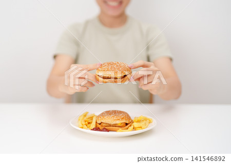 happy woman eating Juicy beef burger with melted cheddar cheese, potato chips. Unhealthy, High calorie, Fast food craving, Obesity, diet, weight loss, junk food and lifestyle 141546892