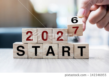 Businessman hand holding wooden cube with flip over block 2026 to 2027 Plans word on table background. Resolution, strategy, solution, goal, business and New Year holiday concepts Businessman hand holding wooden cube with flip over block 2026 to 2027 Plans word on table background. Resolution, strategy, solution, goal, business and New Year holiday concepts 141546955