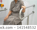 Asian elderly woman use toilet security support rail in bathroom. 141548532