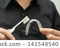 Man clean teeth brace removable retainer with brush. 141548540