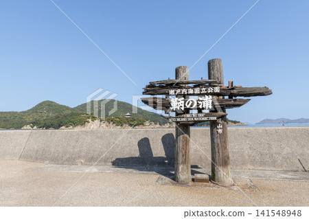 A sign for Tomonoura in Fukuyama City, Hiroshima Prefecture, with Sensuijima Island visible in the background. A sign for Tomonoura in Fukuyama City, Hiroshima Prefecture, with Sensuijima Island visible in the background. 141548948