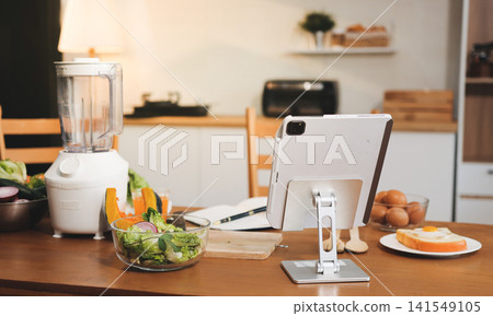 Woman preparing green smoothie in bright kitchen with fresh fruits and vegetables, healthy eating lifestyle moment in natural daylight Woman preparing green smoothie in bright kitchen with fresh fruits and vegetables, healthy eating lifestyle moment in natural daylight 141549105