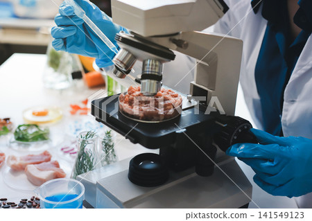 Scientists in lab coats work with plants in a modern lab, focusing on research and experimentation under bright, sterile conditions. Scientists in lab coats work with plants in a modern lab, focusing on research and experimentation under bright, sterile conditions. 141549123
