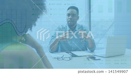 Gesturing man in light-blue shirt explaining financial charts at office desk, laptop glasses Gesturing man in light-blue shirt explaining financial charts at office desk, laptop glasses 141549907