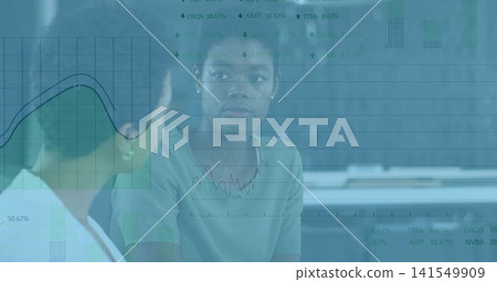 Discussing colleague facing camera wearing muted top at office desk, with line chart overlays Discussing colleague facing camera wearing muted top at office desk, with line chart overlays 141549909