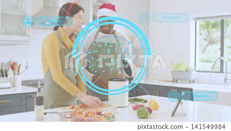 Chopping couple wearing green aprons and Santa hat preparing meal at kitchen island, with cooker 141549984