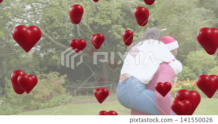 Carrying man in red sweater Santa-hat piggybacking partner in garden, hearts overlay, copy space Carrying man in red sweater Santa-hat piggybacking partner in garden, hearts overlay, copy space 141550026