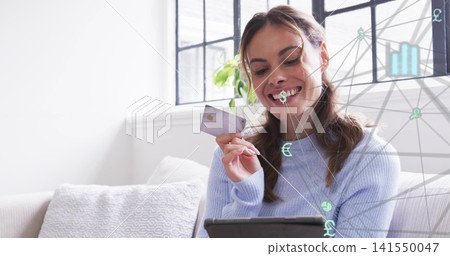 Holding woman in blue knit tapping tablet, showing card amid digital overlay on sofa, copy space Holding woman in blue knit tapping tablet, showing card amid digital overlay on sofa, copy space 141550047