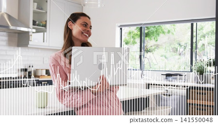 Leaning woman wearing pink robe holding open laptop in home kitchen with mug and waveform overlay Leaning woman wearing pink robe holding open laptop in home kitchen with mug and waveform overlay 141550048