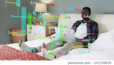 Working man wearing blue plaid shirt on bed at home, using silver laptop with finance overlays 141550050