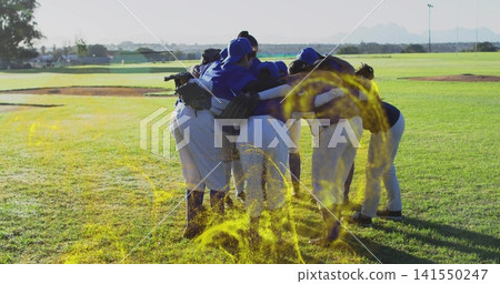 Huddling baseball players linking arms on grassy field near mound, wearing blue jerseys and gloves Huddling baseball players linking arms on grassy field near mound, wearing blue jerseys and gloves 141550247