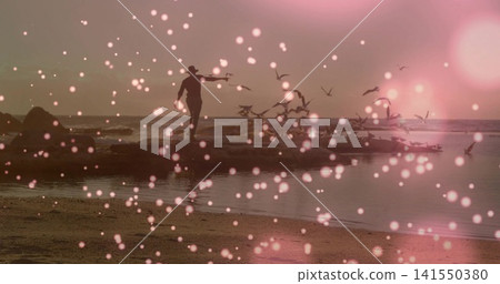 Reaching shadowed man walking on rocky outcrop at shoreline, brimmed hat, birds lifting, pink bokeh Reaching shadowed man walking on rocky outcrop at shoreline, brimmed hat, birds lifting, pink bokeh 141550380