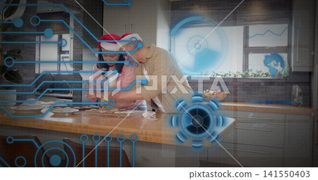 Preparing holiday cookies, woman and man wearing Santa hats at island in kitchen with blue AR Preparing holiday cookies, woman and man wearing Santa hats at island in kitchen with blue AR 141550403
