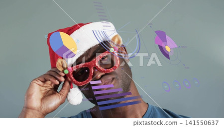 Tilting man adjusting glitter sunglasses in studio, in red Santa hat, blue T-shirt with data charts Tilting man adjusting glitter sunglasses in studio, in red Santa hat, blue T-shirt with data charts 141550637