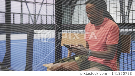 Sitting player in coral shirt, checking device on bench at court with bag, balls, copy space Sitting player in coral shirt, checking device on bench at court with bag, balls, copy space 141550758
