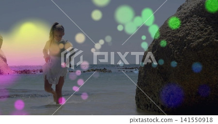Wading child wearing white dress and ponytail walking knee-deep in coastal water, boulder and bokeh Wading child wearing white dress and ponytail walking knee-deep in coastal water, boulder and bokeh 141550918