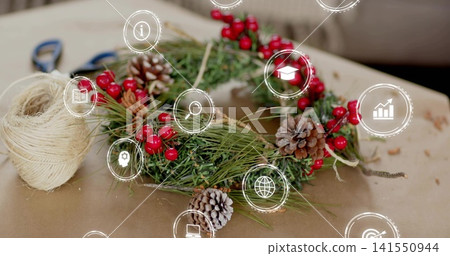 Showing handmade evergreen wreath on kraft paper, with twine spool, blue scissors, overlay icons Showing handmade evergreen wreath on kraft paper, with twine spool, blue scissors, overlay icons 141550944