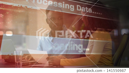 Talking team in mustard top, blue shirt checking papers at office with laptop, data overlay 141550987