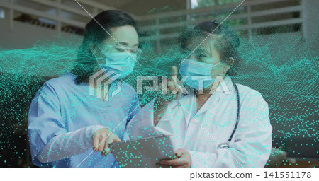 Reviewing tablet masked team in scrubs and labcoat pointing in clinic with teal overlay stethoscope Reviewing tablet masked team in scrubs and labcoat pointing in clinic with teal overlay stethoscope 141551178