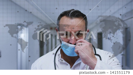 Lowering blue surgical mask, doctor in clinic corridor, with white coat, stethoscope, map overlay Lowering blue surgical mask, doctor in clinic corridor, with white coat, stethoscope, map overlay 141551179