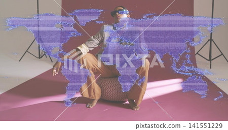 Sitting Indian model wearing shades, posing on pouf in studio with purple world map overlay casting Sitting Indian model wearing shades, posing on pouf in studio with purple world map overlay casting 141551229