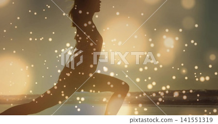 Lunging adult woman exercising on ocean shoreline, wearing activewear, wet sand reflecting sunlight Lunging adult woman exercising on ocean shoreline, wearing activewear, wet sand reflecting sunlight 141551319