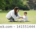 A mother wiping her daughter's hands on the grass. 141551444