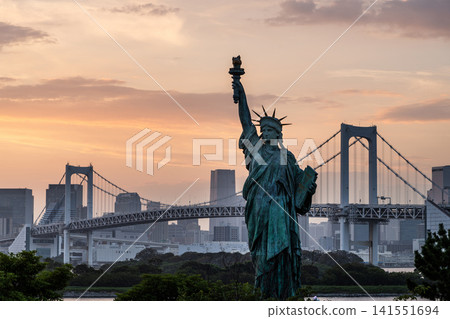 Sunset view of the French Statue of Liberty replica at Odaiba Seaside Park, Minato City, Tokyo, Japan, with the Rainbow Bridge in the background. Sunset view of the French Statue of Liberty replica at Odaiba Seaside Park, Minato City, Tokyo, Japan, with the Rainbow Bridge in the background. 141551694