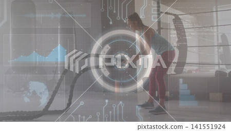 Swinging woman wearing tank top and leggings in gym studio, holding battle ropes, HUD, copy space Swinging woman wearing tank top and leggings in gym studio, holding battle ropes, HUD, copy space 141551924