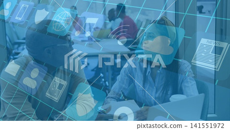 Discussing pair wearing blue shirt and sweater at shared table, using laptop, pen, digital icons Discussing pair wearing blue shirt and sweater at shared table, using laptop, pen, digital icons 141551972