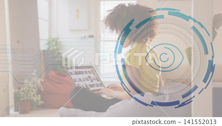 Working woman in yellow top, dark pants typing on laptop on sofa at home, HUD overlay Working woman in yellow top, dark pants typing on laptop on sofa at home, HUD overlay 141552013