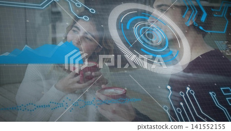 Smiling two women in light and dark sweaters, holding red frothy mugs on couch, AR overlays 141552155