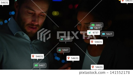 Reviewing colleagues in business attire examining smartphone at night, with floating social badges Reviewing colleagues in business attire examining smartphone at night, with floating social badges 141552178