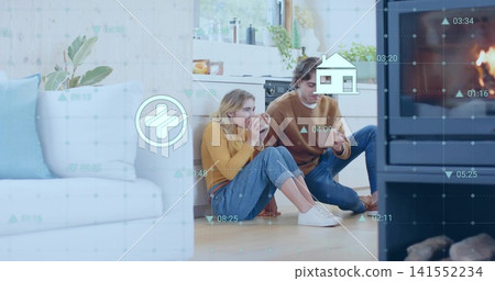 Sitting couple sipping ceramic mugs on wood floor near stove, in mustard sweater showing AR overlay Sitting couple sipping ceramic mugs on wood floor near stove, in mustard sweater showing AR overlay 141552234