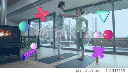 Practicing two women balancing on mats in living room, in athletic wear with floating AR shapes Practicing two women balancing on mats in living room, in athletic wear with floating AR shapes 141552235