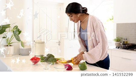 Chopping mid adult Indian woman wearing pink cardigan preparing veg in kitchen, knife, copy space Chopping mid adult Indian woman wearing pink cardigan preparing veg in kitchen, knife, copy space 141552299