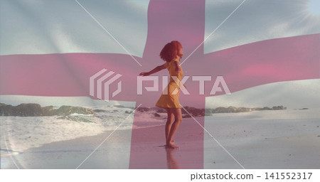 Standing woman in yellow sleeveless dress extending arms on sandy shoreline with pink cross overlay Standing woman in yellow sleeveless dress extending arms on sandy shoreline with pink cross overlay 141552317