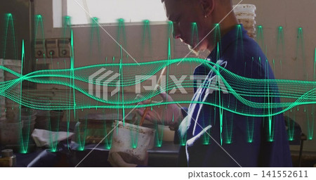 Stirring worker in blue shirt at workshop bench holding white tub, tool, green waveform, copy space Stirring worker in blue shirt at workshop bench holding white tub, tool, green waveform, copy space 141552611