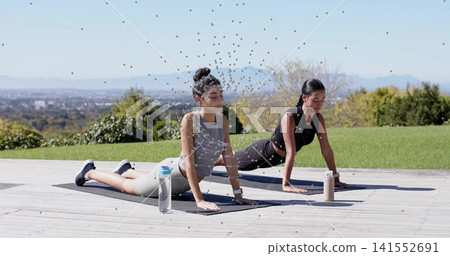 Exercising two women in sportswear lifting torsos on wooden deck, on black mats with water bottles 141552691